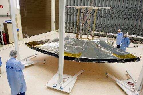 On 29 June 2009 the qualification model (QM) of Gaia's deployable sunshield arrived at the ESTEC test facilities for thermal tests inside the Large Space Simulator (LSS). Before the tests inside the LSS, a deployment test of the QM sunshield was performed in the cleanroom. This view shows the QM sunshield at the end of this deployment test. Clearly visible at this angle is that the sunshield has two parallel blankets of multi-layer insulation (MLI). The Sun-side MLI blanket is now facing the ground and the shadow-side blanket is facing up. To simulate weightlessness, the three rectangular frames of the QM sunshield are each attached to an overhead pulley and a counterweight, supported by three masts standing next to the sunshield. ***** 23 July 2009 ***** credits: ESA