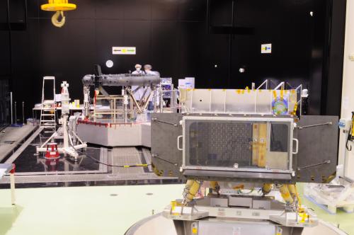 This photograph shows the structural model (SM) of the Gaia focal plane assembly (FPA) in the foreground and the flight model of the Gaia torus in the background, in the cleanroom at Astrium, Toulouse. This front view of the FPA shows the focal plane itself (which is about 1m × 0.5 m), surrounded by the black, box-shaped, radiator, with two more black radiator wings on either side. The radiators are used for passive cooling of the focal plane CCDs. A clear protective cover is in place on the front of the box-shaped radiator. The silver-coloured panel behind the focal plane is a radiator used for passive cooling of the FPA electronics that are also housed behind the focal plane. The six yellow 'tubes' underneath the FPA are the FPA support struts used to mount the FPA on the Gaia torus.
The 3-metre diameter flight model (FM) of the Gaia torus is a key structural element that will support the two Gaia telescopes and the FPA.  ***** 19 November 2010 ***** credits: Astrium
